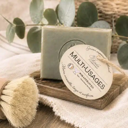 Savon solide multi-usage saponifié à froid Le Multi-Usages, posé sur un porte-savon en bois avec une brosse en fibres naturelles